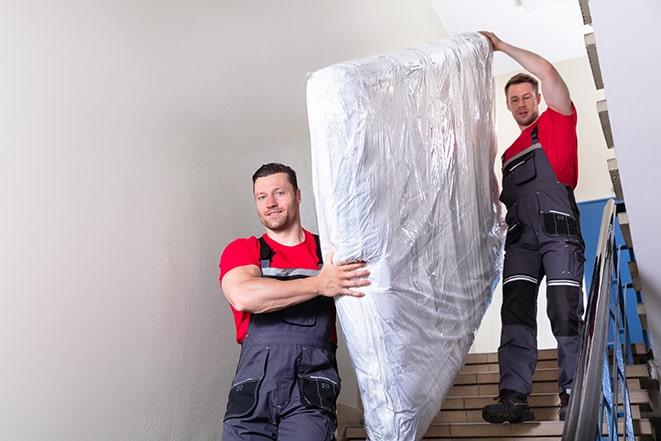 two workers lifting a box spring onto a truck in Hunt